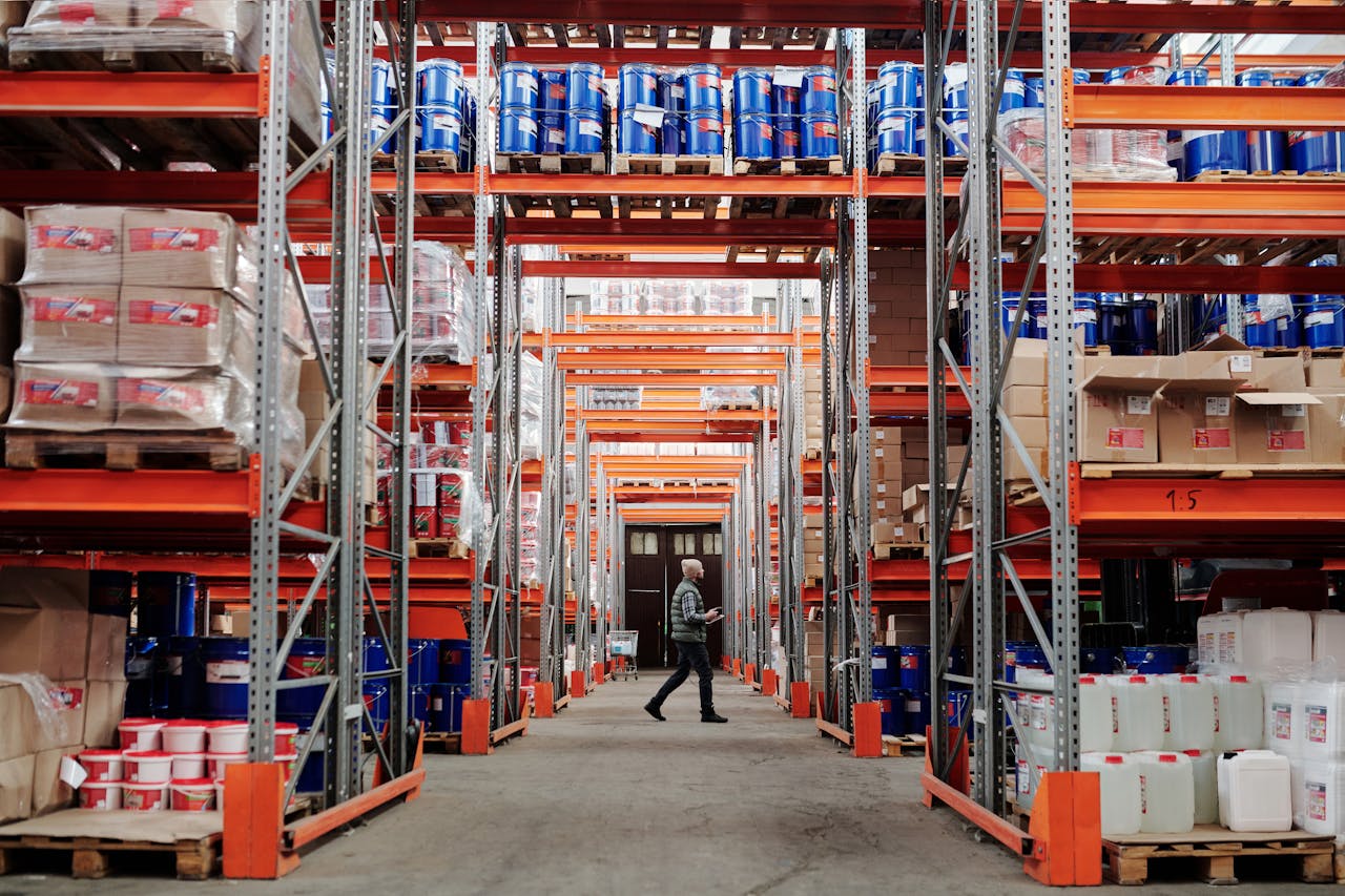 The Art of Drawing Readers In: Your attractive post title goes here A man walking through a large industrial warehouse with stacked shelves filled with goods and products.