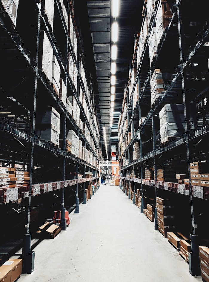 Mastering the First Impression: Your intriguing post title goes here A wide aisle in a large warehouse filled with stacked boxes on high shelves.